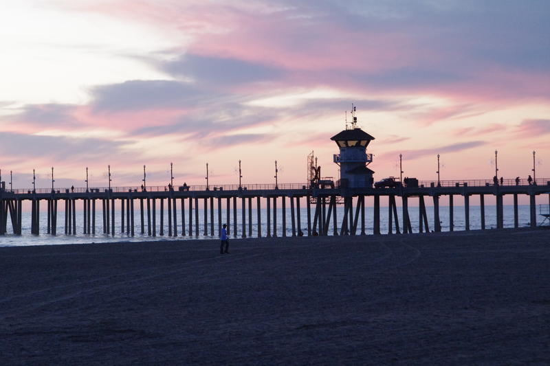 sunset through the pier structure and lifeguard tower at huntington beach pier