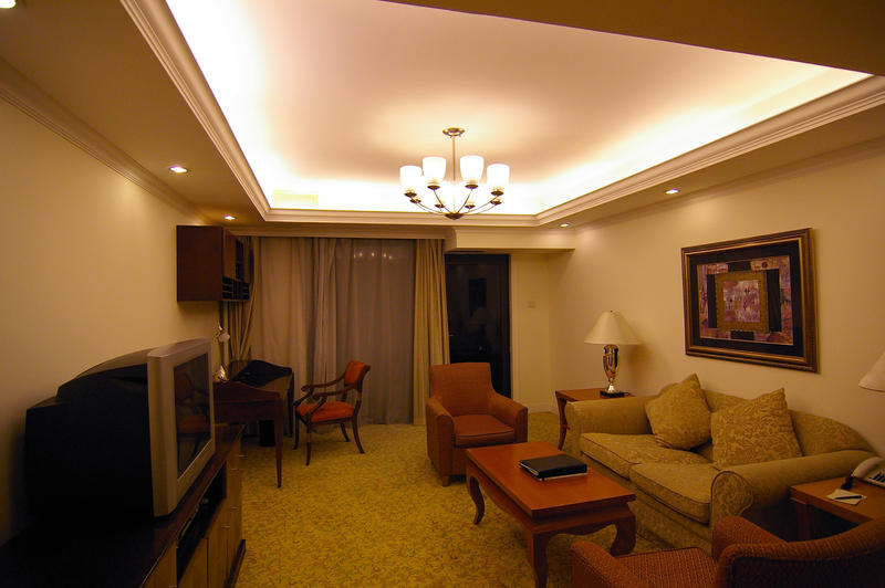 a living room in a high rise apartment at night, soft chairs, tv and settee