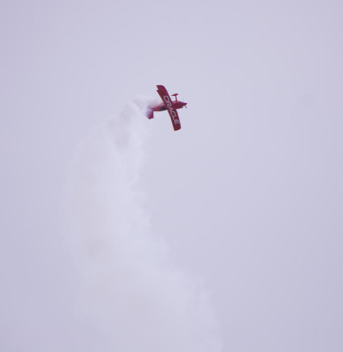 editorial use only: a small red biplane performing a stunt display at an airshow