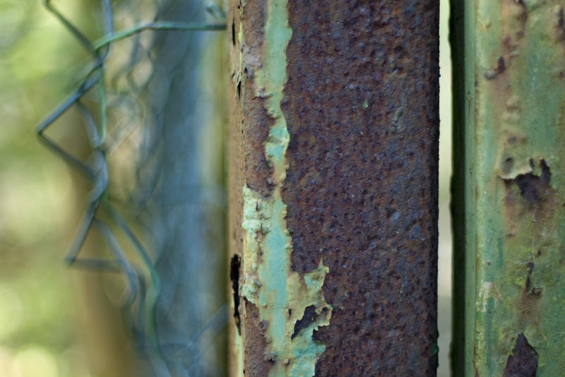 close up on a rusted metal gate and damaged chain link wire fence