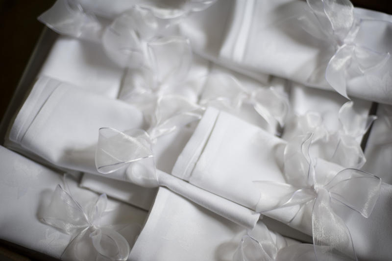 a pile of white ribbon wrapped table napkins