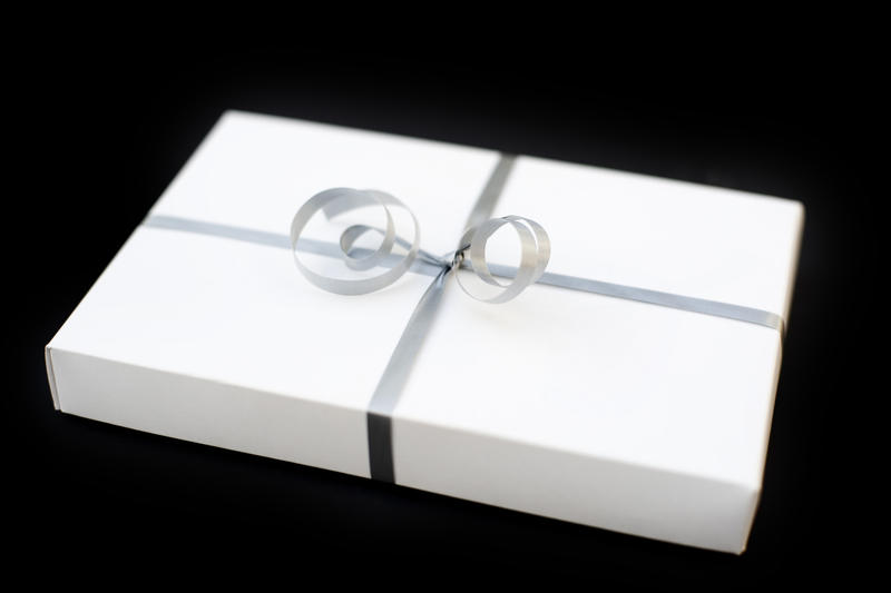 a white gift box wrapped in silver ribbon with a bow