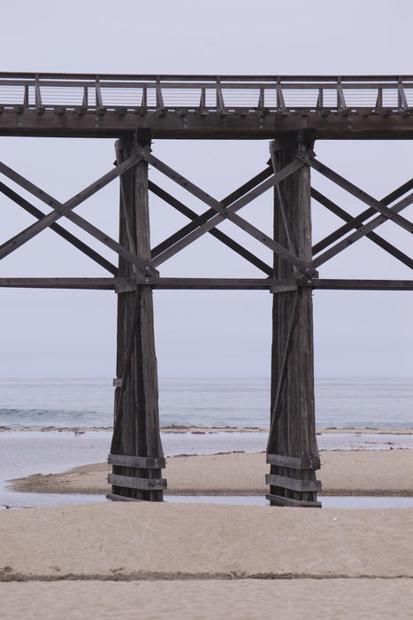 a wooden pier sticks out into the pacific on the california coast