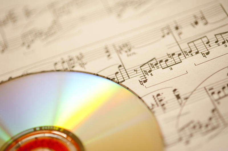 a background image of a piece of sheet music an a CD pictured with a narrow depth of field