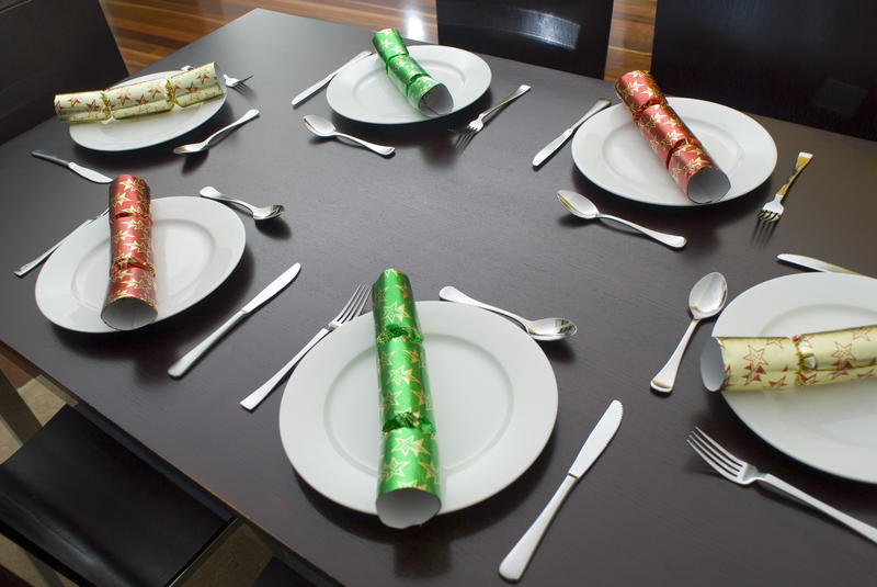 a modern dining table and chairs set up for dinner with colorful christmas crackers