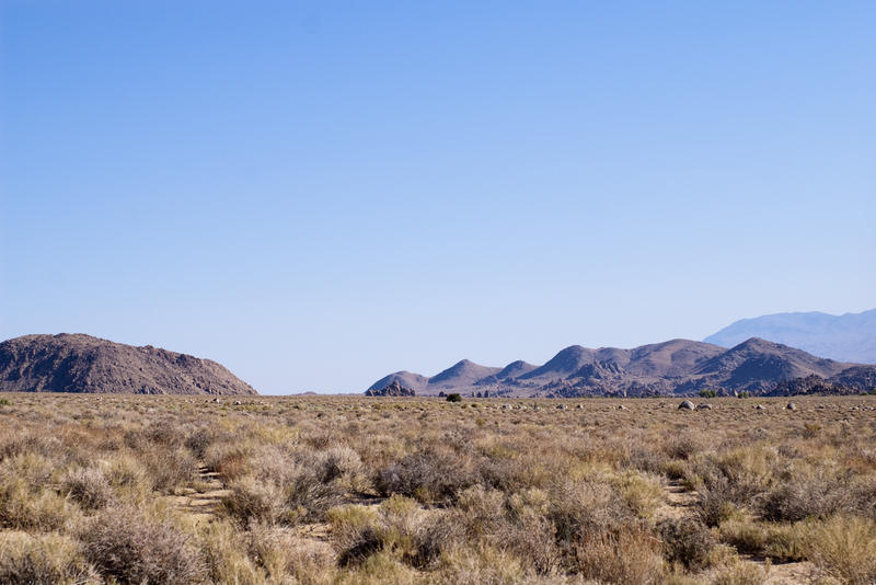 a flat desert landscape with hills and mountains in the distance
