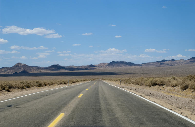 a long straight desert road disappears into the distance
