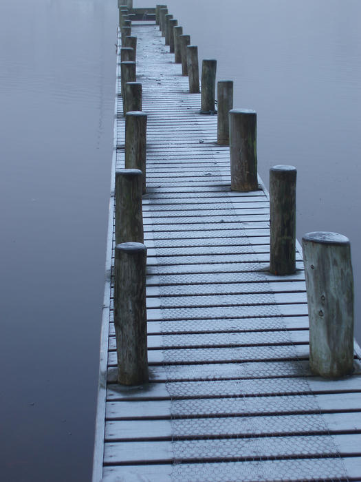 a small wooden jetty covered in frost on a winter day