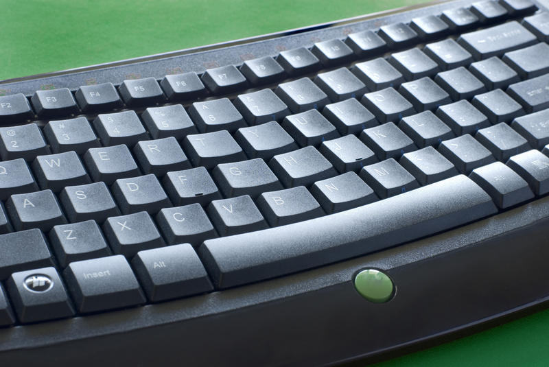 a black coloured computer keyboard on a green background
