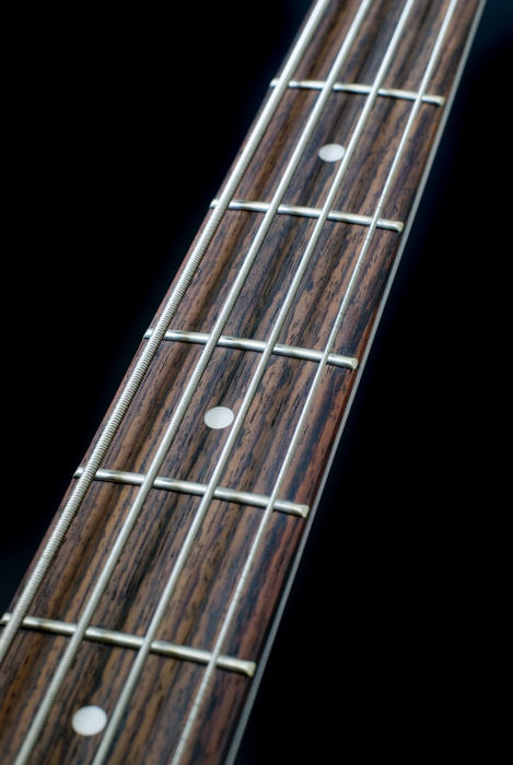 the neck of a bass guitar on a black backdrop