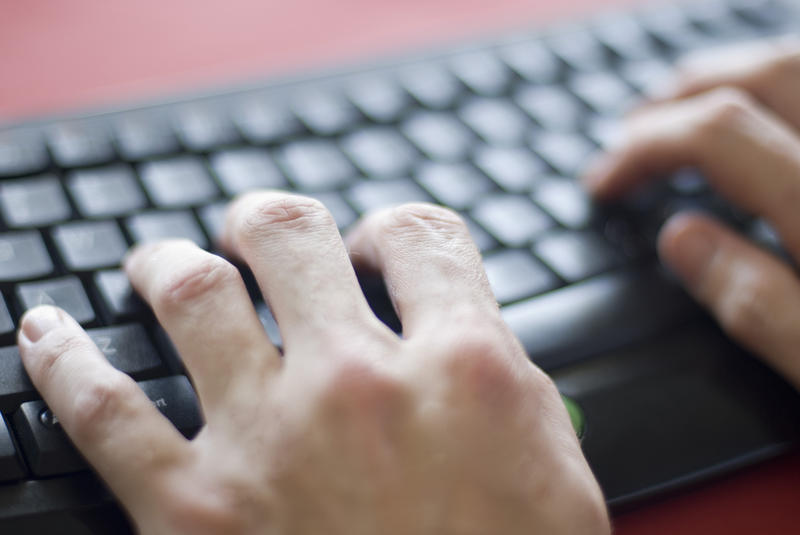 a narrow depth of field image of a user typing at a keyboard with focus on the hands