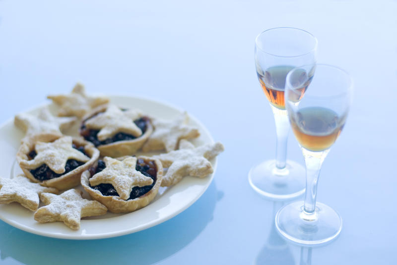 a plate of christmas mince pies and biscuits and glasses sherry