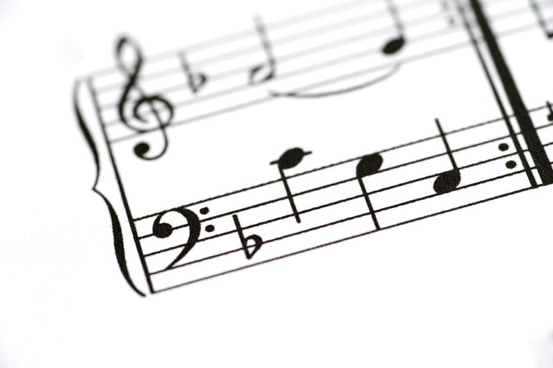 a close up image of a sheet of printed music with the focus on the base clef on a music staf