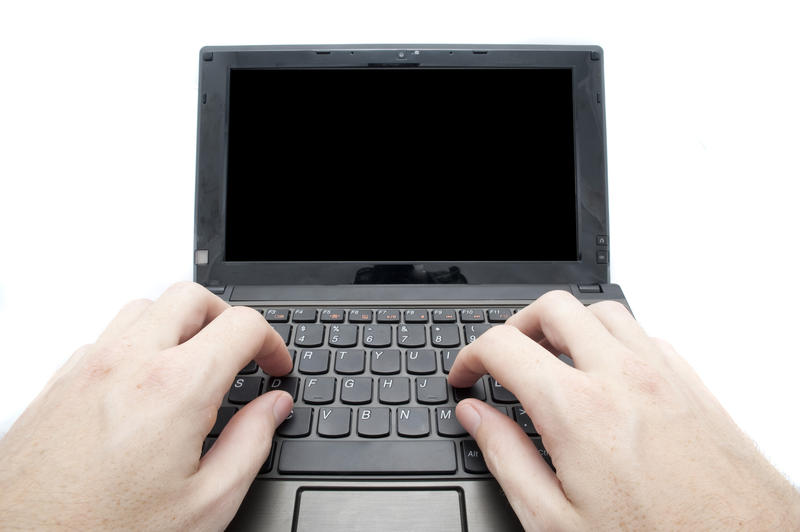 two hands typing on a small netbook computer