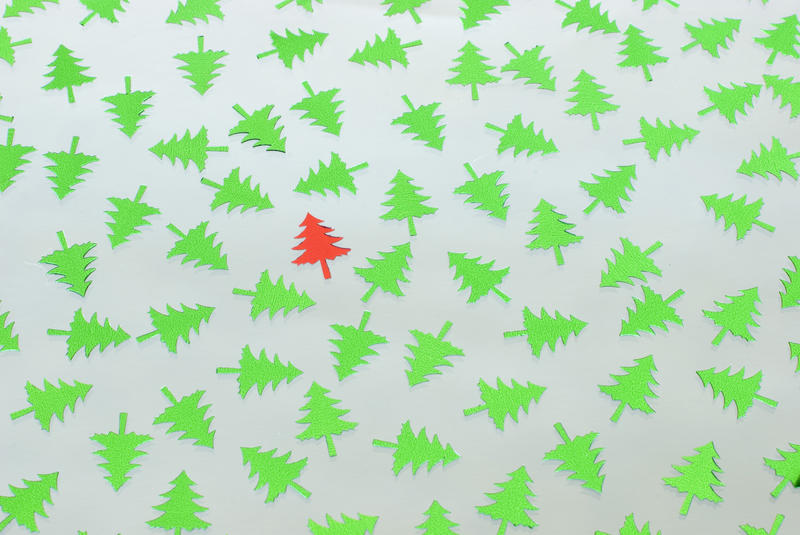 a single red tree on a background of green pine tree shapes