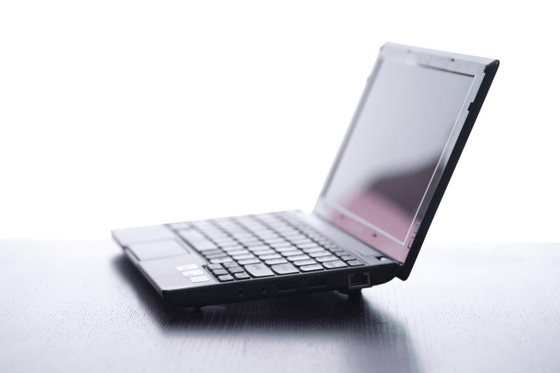 a netbook computer resting on a table pictured with a slihouette lighting effect