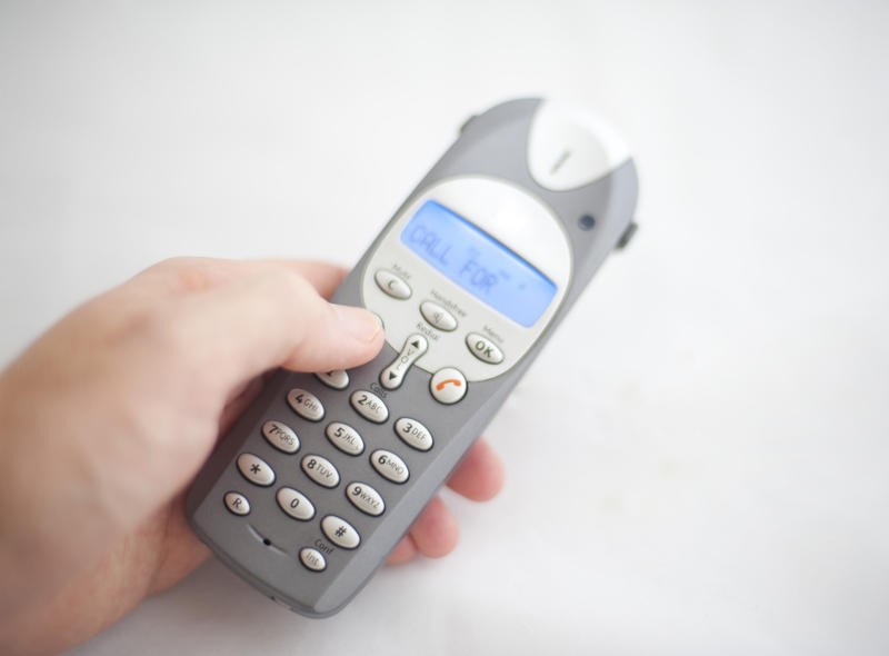 a hand holding a cordless phone taking a call