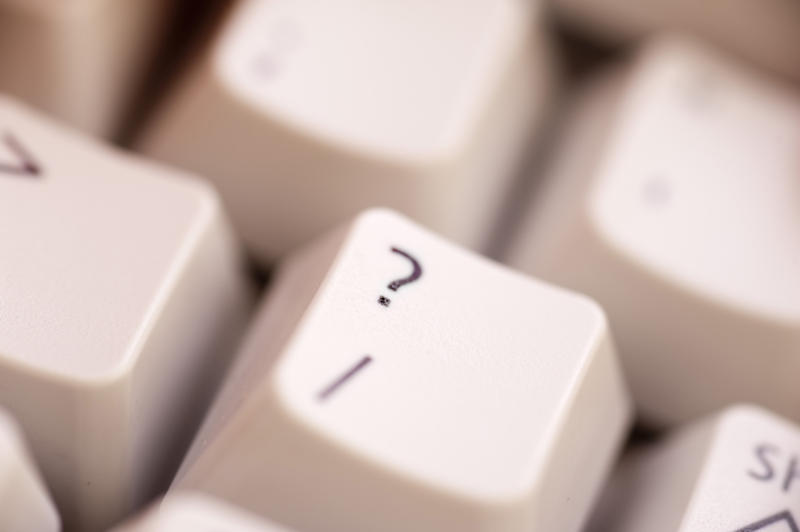 a keyboard question mark key under warm colour lighting