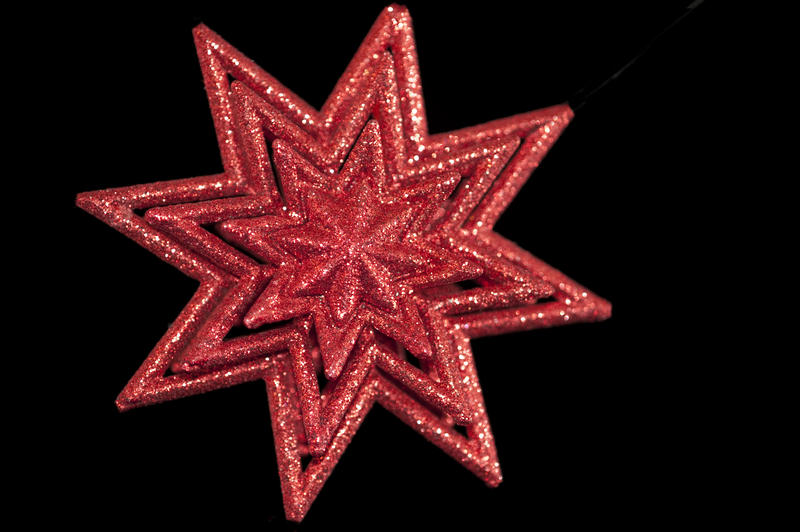 a red coloured christmas star shaped decoration on a black backdrop