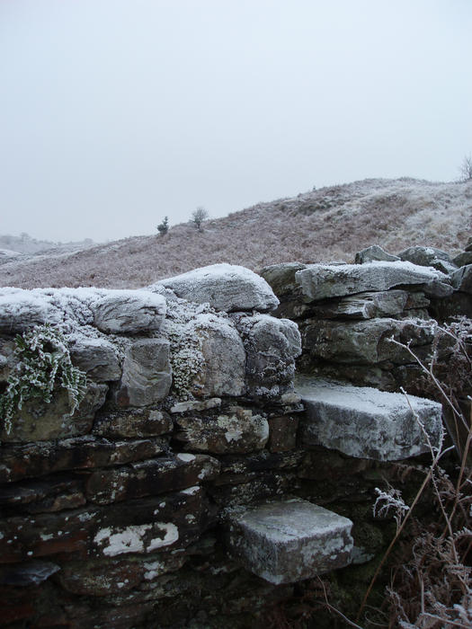 a stone stile in a dry stone wall, pictured in mid winter