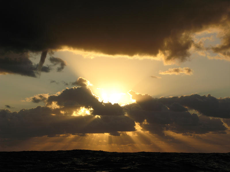 sunbeams breaking through a cloud in a stormy ocean