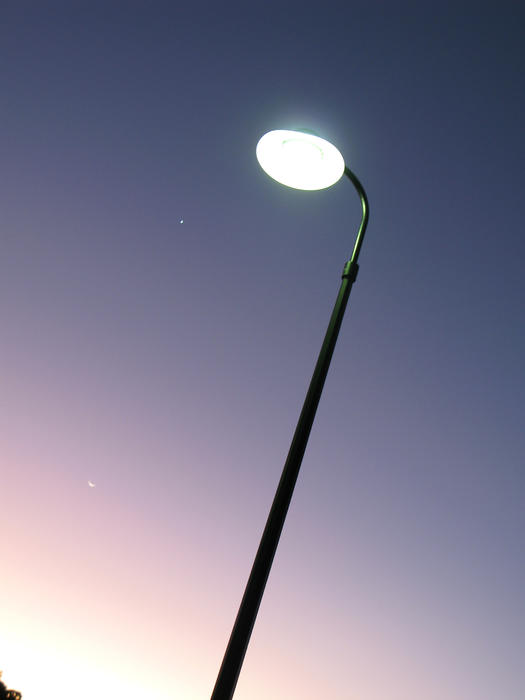 an illuminated streetlamp against a twilight sky