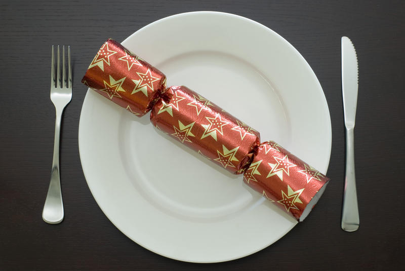 a table setting with a knife, fork, plate and a christmas cracker