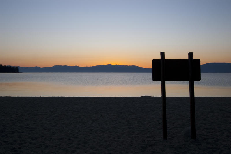 sunset over a sign on the banks of lake tahoe, copyspace