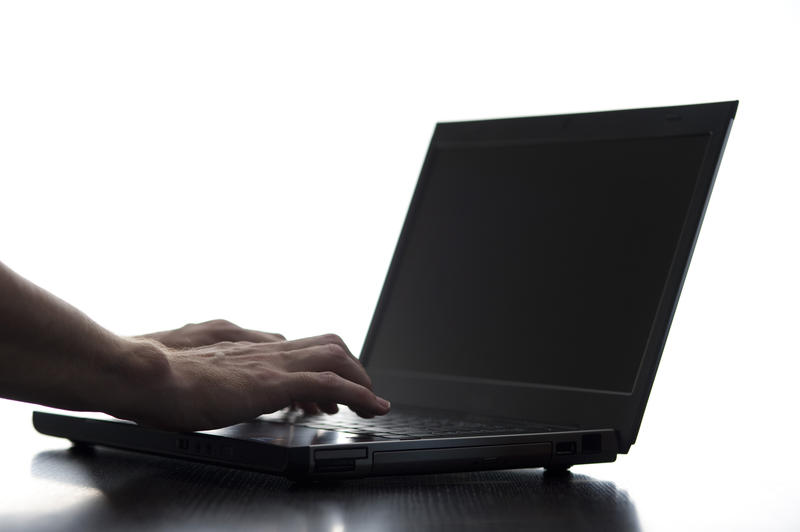 male hands typing at a laptop computer with space for text on a blank screen