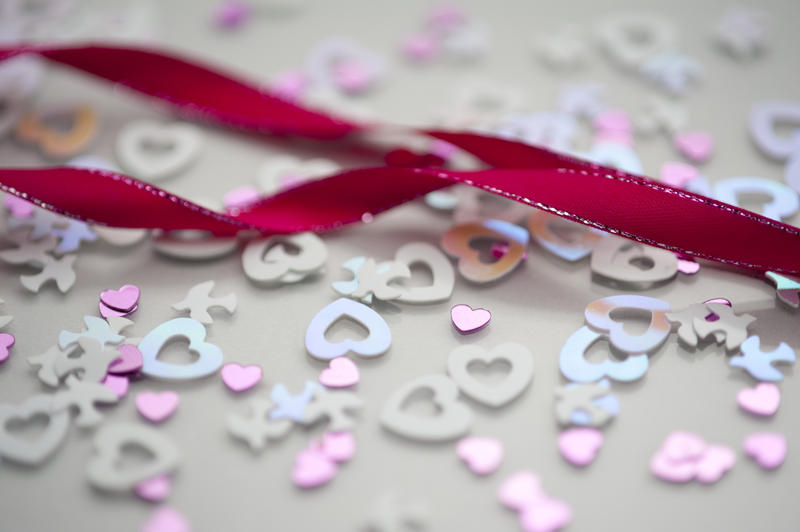 a background image of pink twisted ribbon and wedding confetti shapes