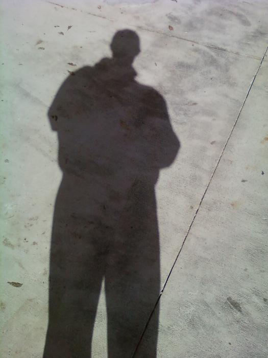 <p>&nbsp;Man's shadow on concrete walkway</p>