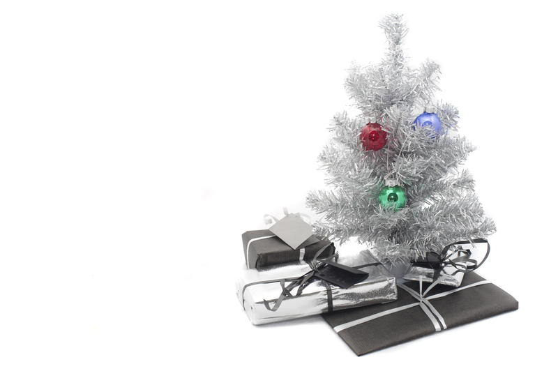 a small artificial silver tinsel christmas tree with presents inderneath