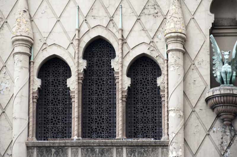 decorative moorish style grilled window and a decorative winged dragon on guard, architectural details on an old building