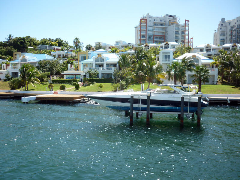 a luxury motor boat on a boat lift out the front of a somewhat ugly waterfront home - not proiperty released