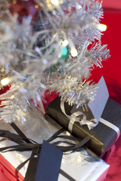 an arrangement of gifts beneath an artificial christmas tree