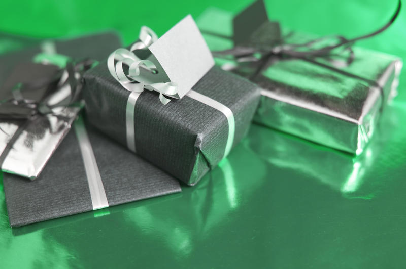 a trio of wrapped chritmas presents on a green coloured reflective background
