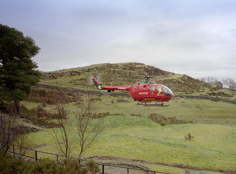 A red air ambulance helicopter landing in a field