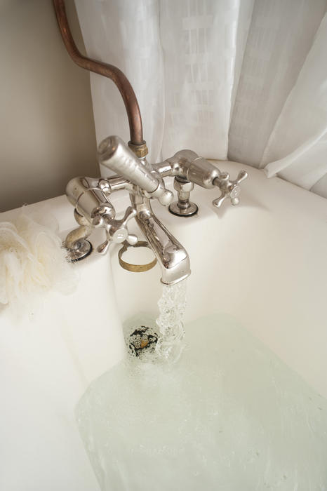 Retro bathroom tap mounted on a bathtub with inviting hot water filling the bath