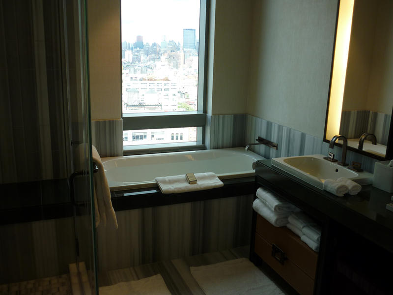 Bath with a view in a hotel bathroom with a large window over the bathtub and neatly laid out linen and towels