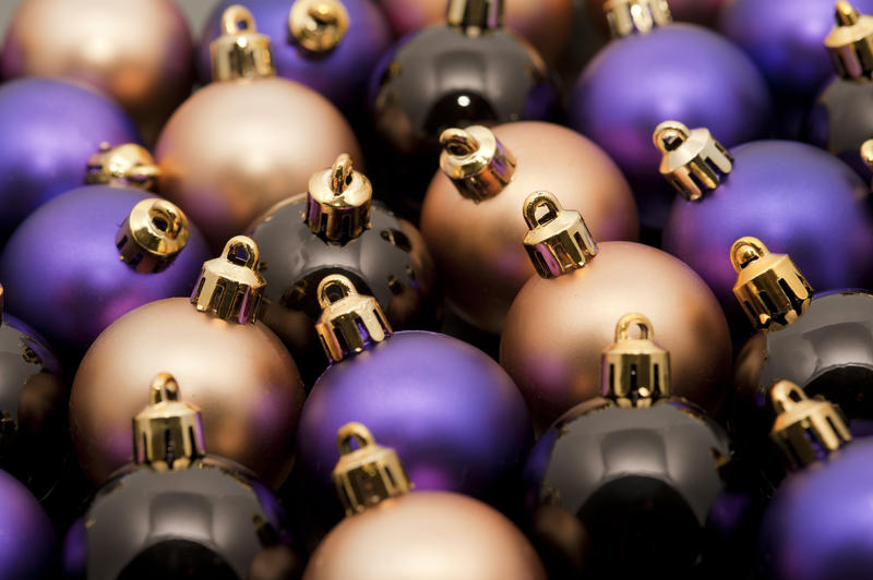 Christmas bauble background with closely packed decorations in gold, black and purple in a random pattern