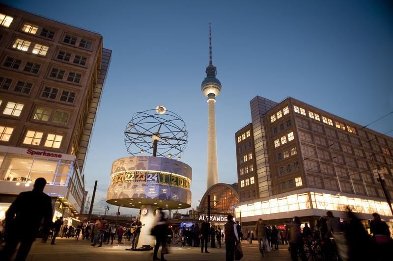 Nighttime view of crowds of people in the Alexanderplatz, Berlin with the International World Clock in the foreground and landmark Berlin TV tower behind