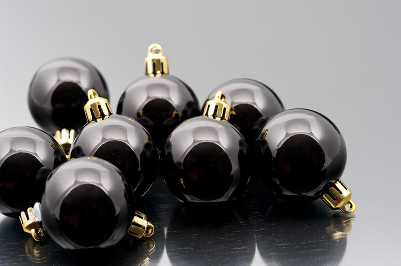 Collection of shiny black Christmas baubles on a reflective surface with copyspace