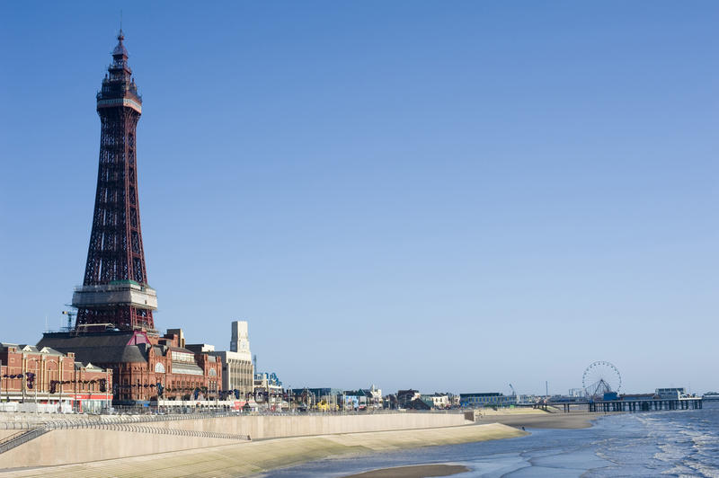View along the sandy beach of the Blackpool watefront with the pier and Blackpool Tower on a beautiful sunny day with clear blue sky