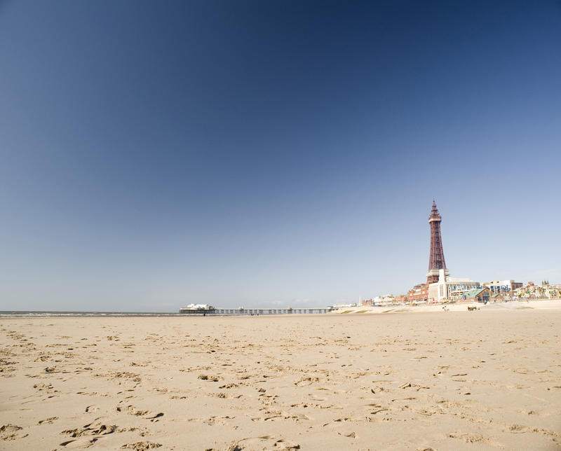 View along the deserted golden sand of Blackpool Beach towards the historical Blackpool Tower in Lancashire, England