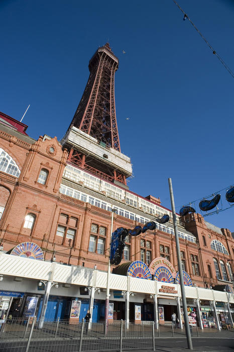 Low angle oblique view of the front facade of a Blackpool amusement arcade with the historical Blackpool Tower rising above it