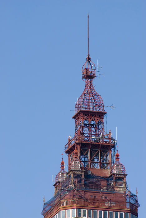 Detail of the intricate ornate Victorian architecture of the spire of the historical Blackpool Tower against a clear blue sky with copyspace