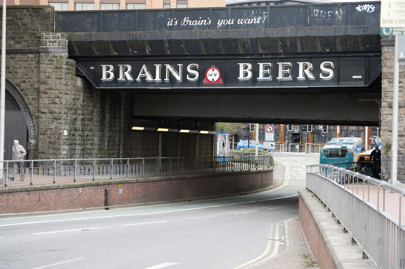 Urban street underpass with traffic and an overhead banner advertisement for Brains Beer