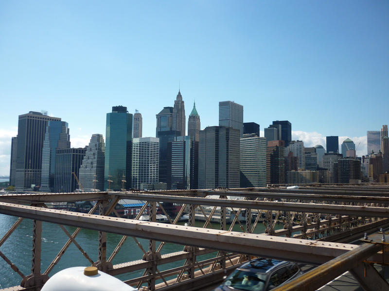View of the skyscrapers of downtown Manhattan from Brooklyn Bridge under a clear blue sunny sky