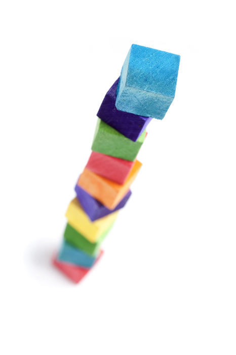 Looking down on a tower built of colourful toy building bricks, with intentional shallow depth of field and isolated over a white background