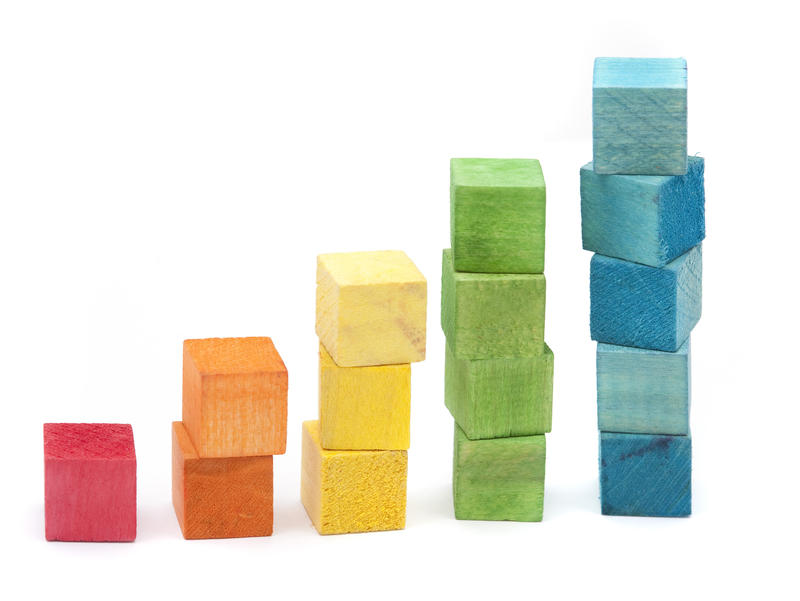 Colourful wooden building blocks stacked in increasing height using individual colours as an educational toy for young children